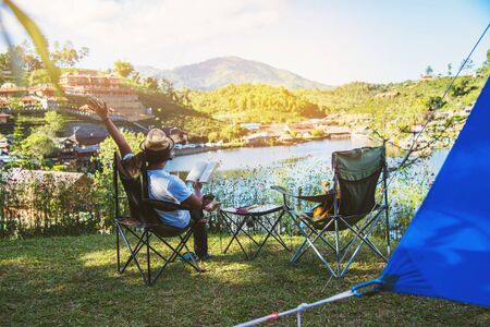 Asian men tourists camping and And working notebook, She is happy, relaxed, enjoying reading a book,...