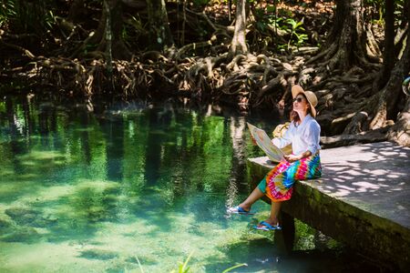 Asian women travel relax, travel nature in the holiday. women enjoying Sitting and watching the travel map the lake mangrove forest. tha pom-klong-song-nam at krabi. summer, Mapの写真素材