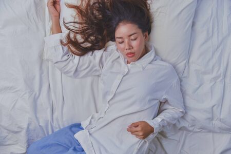 Young Woman Sleeping In Bed. Top view of young woman lying down sleeping well in bed. sleeping relax, young smiling pretty lady lies in bed.の写真素材