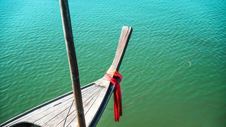 Photos of the bow ship head with red cloth tied. View from head of traditional wooden boat with red...