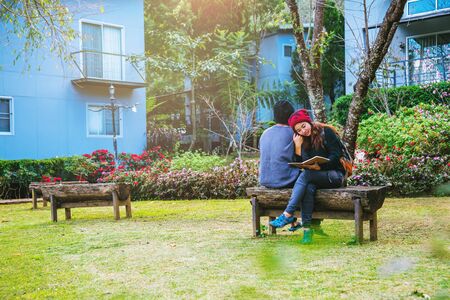 Asian couple smiled and was happy with the book read. Among the beautiful flower gardens, Valentineの写真素材