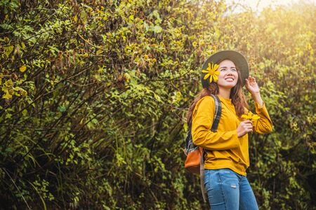 Asian tourist nature, relaxing enjoying the fresh beauty of flower. She smiled and hand picked Bua Tong flower yellow.の写真素材