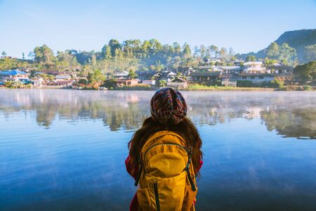 The woman standing near the lake, she was smiling, enjoying and enjoying the natural beauty of the mist.の写真素材