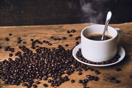 Top view Hot black coffee on a old kitchen table. background concept Coffee cup and and coffee beans on wooden table. Coffee beans spread on the table.の写真素材