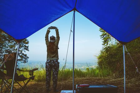 Travel relax in the holiday camping on the Mountain. Young woman tourists camping relax On the Moutain in the jungle. nature green mountains range camping tent.の写真素材