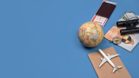 Tourist planning vacation with the help of world map with other travel accessories around. smartphone, film camera and sunglasses on a Blue background.の写真素材