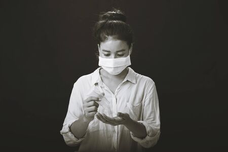 A picture of a girl in the studio wearing protection face mask against Resist infection coronavirus and Cleaning her hands with sanitizer gel.の写真素材