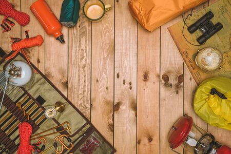 Traveler's camping accessories Essential vacation items. Wanderlust, safari equipment postcard, poster, tent, wooden background. camera, hat, map, compass, mobile phone, boots, lanternの写真素材