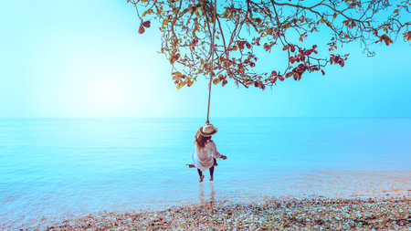 Happy traveler asia woman in swing  relaxing  and looking beautiful nature landscape. Andaman sea. phuke. Tourist sea beach Thailand, Asia, In summer.の写真素材