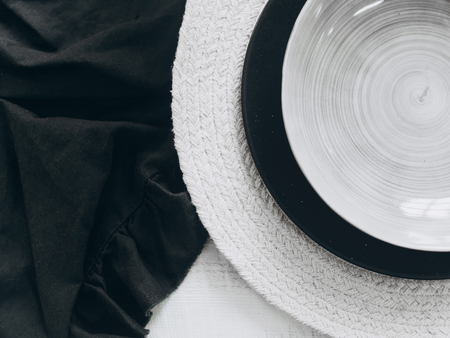 Empty gray and black vintage plates on a plate mat on a white wooden table background. Top view, horizontalの写真素材