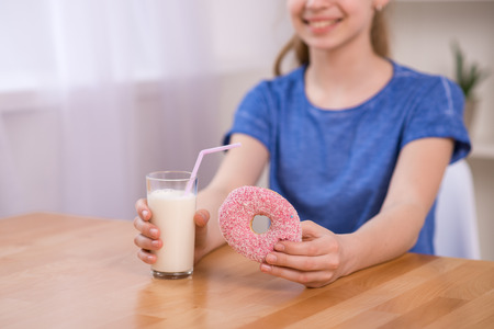 Portrait of happy girl having milk and cookies as breakfast. Young woman indoors living lifestyle at home.の写真素材