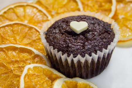 Chocolate muffin with dried orange slices on white plate.の写真素材