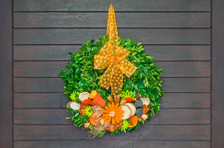 Spring wreath with orange bow hanging on dark wooden doorの写真素材