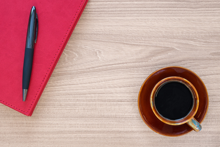 Coffee cup and notebook with pen on wood deskの写真素材