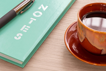 Coffee cup and notebook with pen on wood deskの写真素材