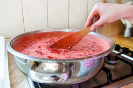 Girl cooks strawberry jam in kitchenの写真素材