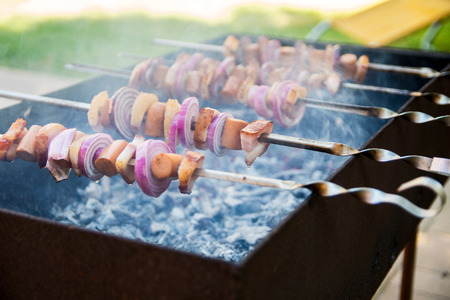 Shashlik with frankfurter, bacon and onion laying on the grillの写真素材
