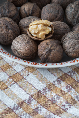 Whole walnuts and walnut kernels in white plate on table with checkered tableclothの写真素材