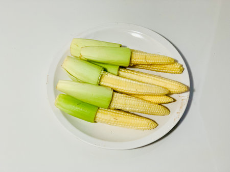 baby corn on white plate isolated on white background, top view.