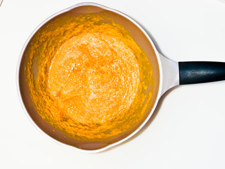 Cooking pumpkin puree in a frying pan on a white backgroundの写真素材