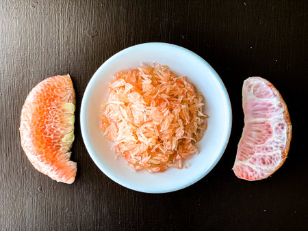 Grapefruit and grapefruit slices in a bowl on a black backgroundの写真素材
