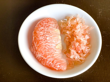 Grapefruit and shavings in a bowl on a wooden tableの写真素材