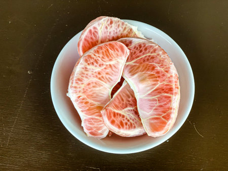 Peeled grapefruit on a white plate on a black background.の写真素材