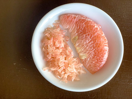 Grapefruit slices in a white plate on a wooden table. pomeloの写真素材