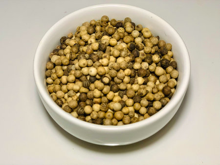 Coriander seeds in a white bowl on a white background.の写真素材