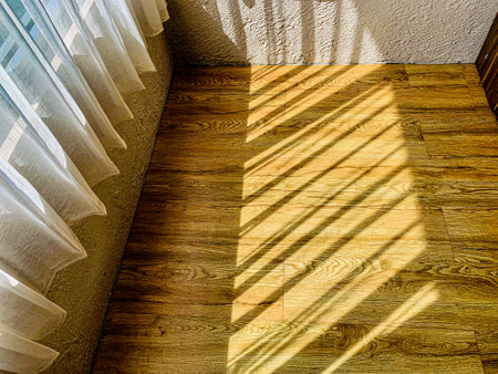 Wooden floor and white curtains in a room with shadow from the windowの写真素材