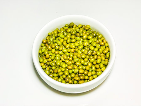 Green mung beans in a white bowl on a white background.の写真素材