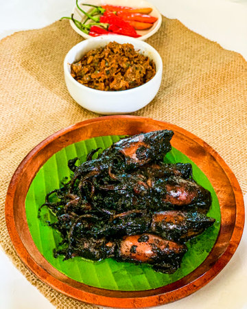 Fried squid with black soy sauce on wooden plateの写真素材