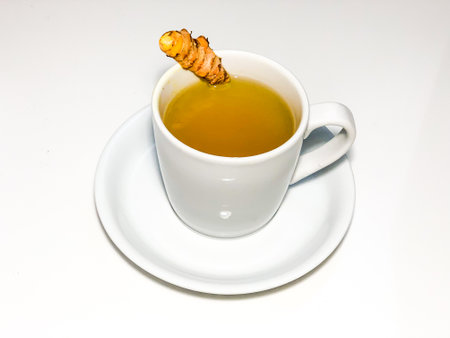 Turmeric tea in a white cup on a saucer on a white backgroundの写真素材