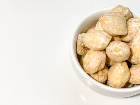 Dried peanuts in a white bowl on a white background with copy spaceの写真素材