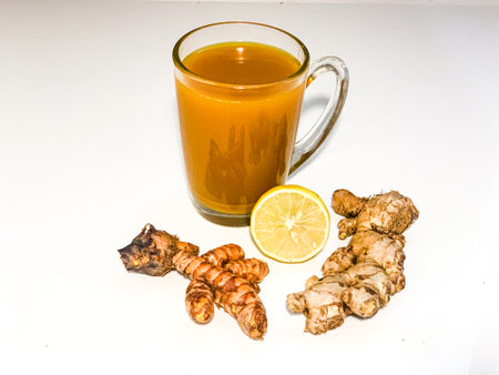 Cup of ginger tea with lemon and ginger root on white background