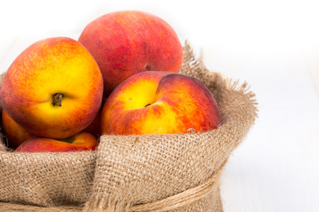 Peaches in basket on sackcloth - on white backgroundの写真素材