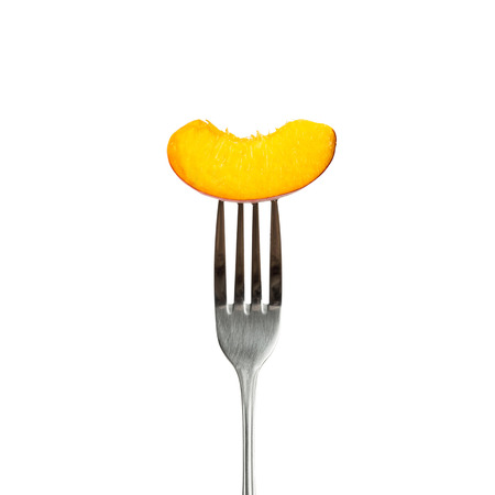 Piece of peach on fork - isolated on white backgroundの写真素材