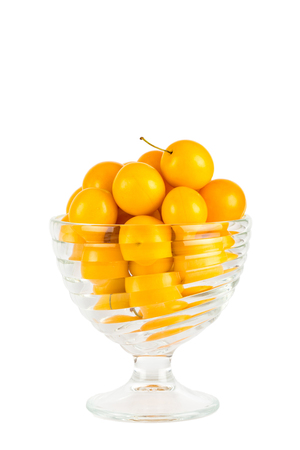Handful of yellow cherry plums in glass bowl - isolated on white backgroundの写真素材