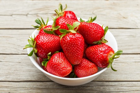 Fresh ripe strawberries in a simple white bowlの写真素材