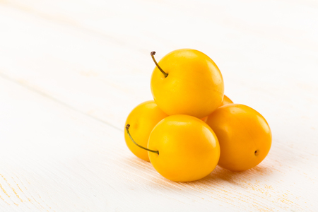Yellow cherry plums on white wooden surfaceの写真素材