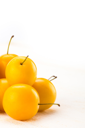Yellow cherry plums on white wooden surfaceの写真素材