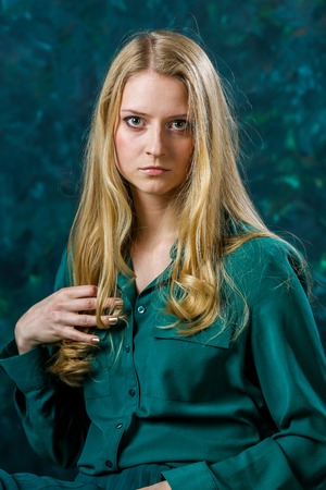 Beautiful Russian blonde girl on a green background in a long green dressの写真素材