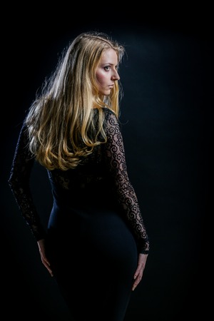 Beautiful Russian blonde girl on a black background in a dark guipure dressの写真素材