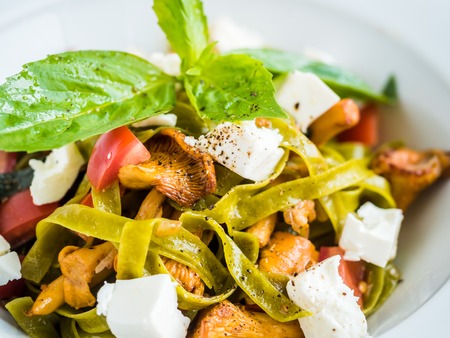 pasta with green pasta with chanterelle mushrooms, feta cheese, tomatoes and pepperの写真素材