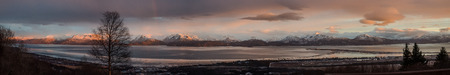 The rays of a setting sun shine on a rain shower over Kachemak Bay Alaska
