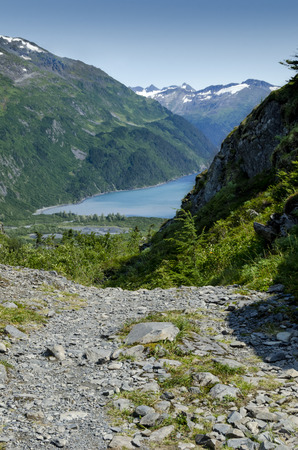 The water of a fjord in Alaska is framed by the surrounding snow cap mountains.の写真素材