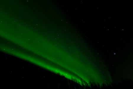 A wall of green light curves across the night sky.の写真素材