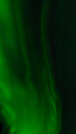 Swirling across the sky, a aurora leaves behind a green mist.の写真素材