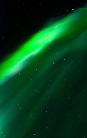 The green glow of an aurora rises like a curtain up the sky.の写真素材