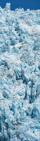 Blue white ice makes a vertical face at the front of a thick glacier.